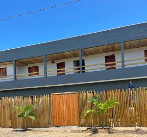 una casa con una recinzione e palme di fronte ad essa di Flats da Ilha Max Rev a Marechal Deodoro