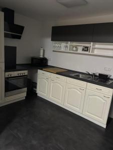 een keuken met witte kasten en een spoelbak bij Ferienwohnung Arnstadt Ost in Arnstadt +6 foto's