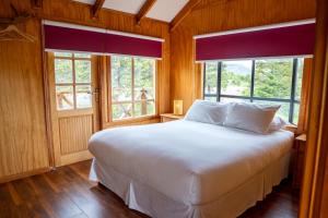 een slaapkamer met een wit bed en 2 ramen bij Hotel Boutique 3 Pasos in Cerro Castillo