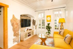 ein Wohnzimmer mit einem gelben Sofa und einem Fernseher in der Unterkunft Leone Stays - Golden Castle Loft in Thun