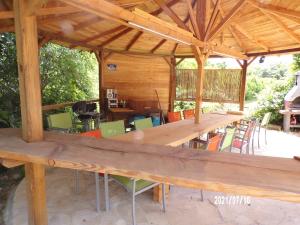 un pavillon en bois avec une longue table et des chaises dans l'établissement Le Mas Hauregard, à La Celle-sous-Gouzon