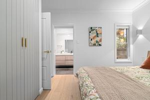 a white bedroom with a bed and a bathroom at Bundeena Bungalow in Bundeena +17 photos