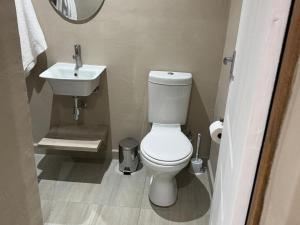 a bathroom with a white toilet and a sink at The Umbrella Shade in Ulundi +7 photos