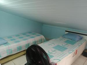 Una pequeña habitación con dos camas y una silla. en Hostel & Cia Itanhaém, en Itanhaém