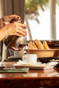 a woman is pouring coffee into a cup on a table at Hotel Ilha do Marajó by Unna in Soure