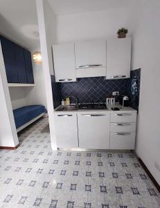 een keuken met witte kasten en een tegelvloer bij VitaDaMare in Giardini Naxos
