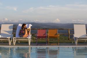a woman sitting in chairs next to a pool at Cascina Marcantonio in Acqui Terme