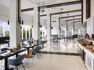 Un restaurante con mesas, sillas y ventanas. en Novotel Kochi Infopark, en Kochi