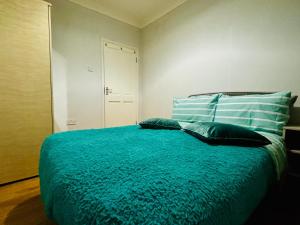 a bedroom with a bed with blue sheets and pillows at Emerald Room - shared bathroom in Ponders End +2 photos