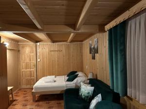a bedroom with a bed and a green couch at Cichowiańska Chałupa przy stoku z widokiem na GÓRY I SKY WALK in Małe Ciche