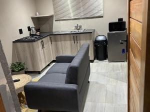 a living room with a couch and a kitchen at The Umbrella Shade in Ulundi
