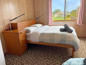 een slaapkamer met een bed, een dressoir en een raam bij 3 Barragoot Street in Bermagui