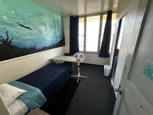 a bedroom with a bed and a desk and a painting at Central YMCA Residences in Honolulu