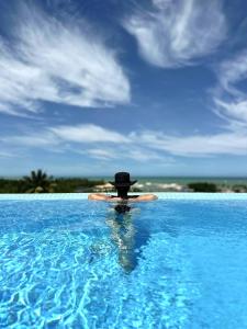 een persoon in een hoed zittend in een zwembad bij Bela Vista Hotel Boutique in Caraíva