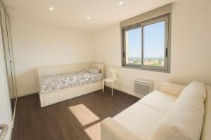 een witte kamer met een bed en een bank bij Douce escale - T3 d exception face mer in Saint-Jean-de-Monts