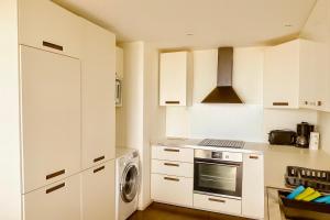 een keuken met witte kasten en een wasmachine en droger bij Douce escale - T3 d exception face mer in Saint-Jean-de-Monts +6 foto's