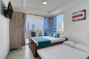 een slaapkamer met twee bedden en een groot raam bij Marèlago Apartamentos in Cartagena