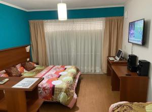 una camera d'albergo con un letto, una scrivania e una televisione di Edificio Colina 1 a Victoria