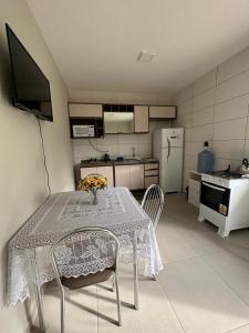 eine Küche mit Tisch und Stühlen und eine Küche mit Kühlschrank in der Unterkunft Pousada Aloha Pinheira in Palhoça