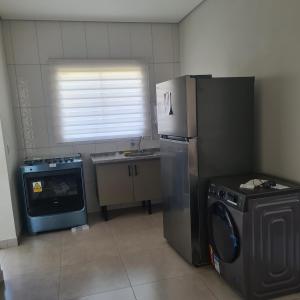 a kitchen with a refrigerator and a washing machine at Casa 1 Montebelle in Porangaba