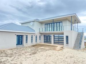 a white house with a blue roof at Khulanathi Guesthouse in Engcobo