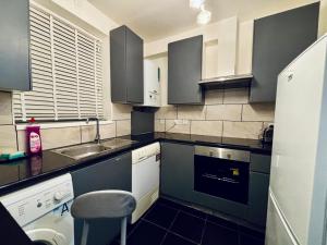 a kitchen with blue cabinets and a sink and a stool at Obsidian Room - shared bathroom in Ponders End