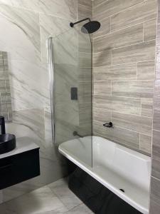 a bathroom with a tub and a glass shower at Khulanathi Guesthouse in Engcobo +12 photos