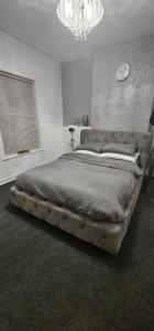 een groot bed in een slaapkamer met een kroonluchter bij Comfy 2 Bedroom House near City Centre and Uclan in Preston