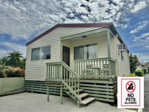 une petite maison avec un panneau indiquant que les animaux domestiques ne sont pas admis dans l'établissement Maclean Riverside Cabin Park, à Maclean 6 autres photos