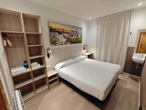 巴塞罗那Hostal BESTPRICE Barcelona Stadium的卧室配有白色的大床和架子