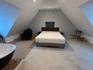 - une chambre mansardée avec un lit et une baignoire dans l'établissement Hotel Aardenburg, à Aardenburg