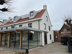 - un grand bâtiment blanc avec des fenêtres en verre devant dans l'établissement Hotel Aardenburg, à Aardenburg