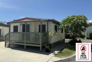 une petite maison avec un panneau indiquant que les animaux domestiques ne sont pas admis dans l'établissement Maclean Riverside Cabin Park, à Maclean