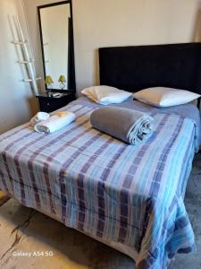 a bed with a plaid blanket and pillows on it at CASA CONCEITO - studio panoramico, suites e quartos in São José