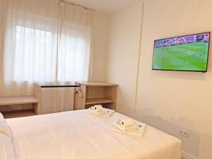 a room with a bed and a tv on the wall at NUEVO -Bogotá Suites- Apartamentos con cocina, AC, 15min del centro a pie in Alicante