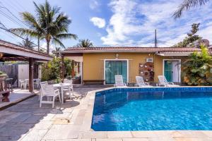 a house with a swimming pool in front of a house at Chalés Kalimmera in Ilhabela