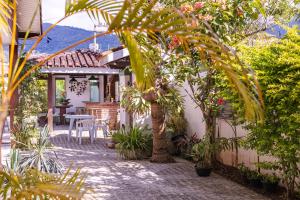 a garden with a table and chairs and plants at Chalés Kalimmera in Ilhabela