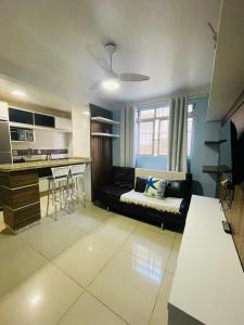 a living room with a black couch and a kitchen at Residencial Nicole in Florianópolis