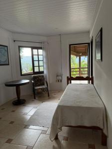 a bedroom with a bed and a table and two windows at Interior beach house in Bombinhas! in Bombinhas +4 photos