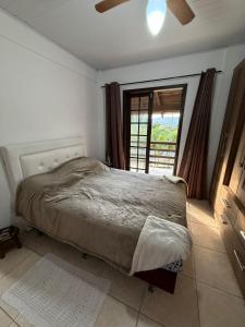 a bedroom with a bed and a large window at Interior beach house in Bombinhas! in Bombinhas