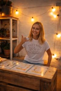 een vrouw die voor een tafel zit bij Doña Rose Surf Hostel in Las Palmas de Gran Canaria