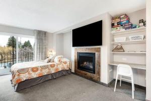 Schlafzimmer mit einem Bett, einem Kamin und einem TV in der Unterkunft River View Condo- Edge of Downtown in Bend