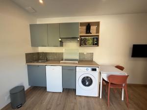 een keuken met een wasmachine en een tafel met stoelen bij T2 Dream in Périgueux