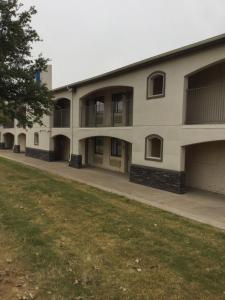 an apartment building with a lawn in front of it at Blue Bonnet Suites -Lubbock, TX - Medical Center in Lubbock