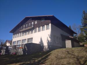 a large white building with a black roof on a hill at Penzion Koniklec in Jestrabi V Krkonosich