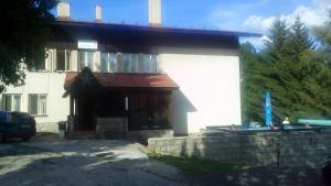 a white building with a blue umbrella in front of it at Penzion Koniklec in Jestrabi V Krkonosich
