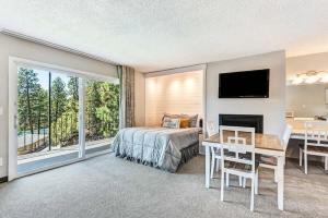 ein Schlafzimmer mit Bett, Schreibtisch und Fernseher in der Unterkunft Riverfront Condo - Pet Friendly Near Downtown in Bend