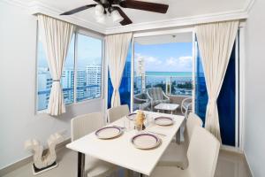 een eetkamer met een witte tafel en stoelen en grote ramen bij Marèlago Apartamentos in Cartagena