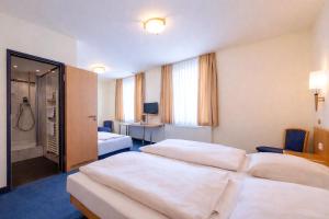 a hotel room with two beds and a desk at Hotel Wendelstein München City in Munich