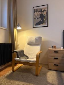 a white chair sitting in a room with a dresser at Cozy Self check-in Apartment in vibrant Ruzinov area, Komárnická 42, Bratislava in Bratislava